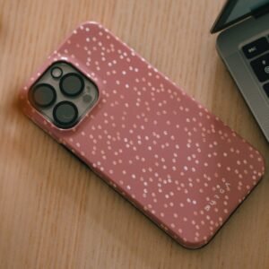 Pink speckled phone case next to laptop